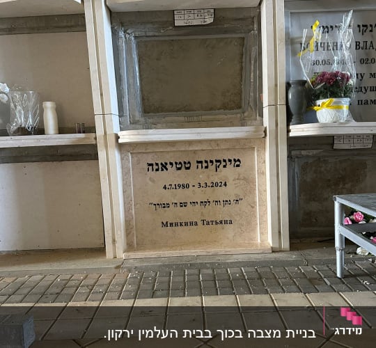 קבר עם כיתוב בעברית ותאריך, פרחים ליד